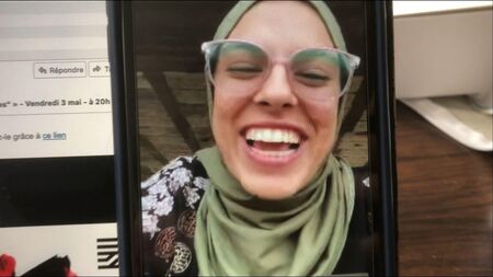 Vrouw met een hoofddoek glimlachend op een video-oproep, met een achtergrond van een bureau.