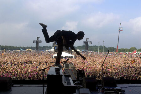 Silhouet van een muzikant die optreedt voor een groot publiek tijdens een festival.