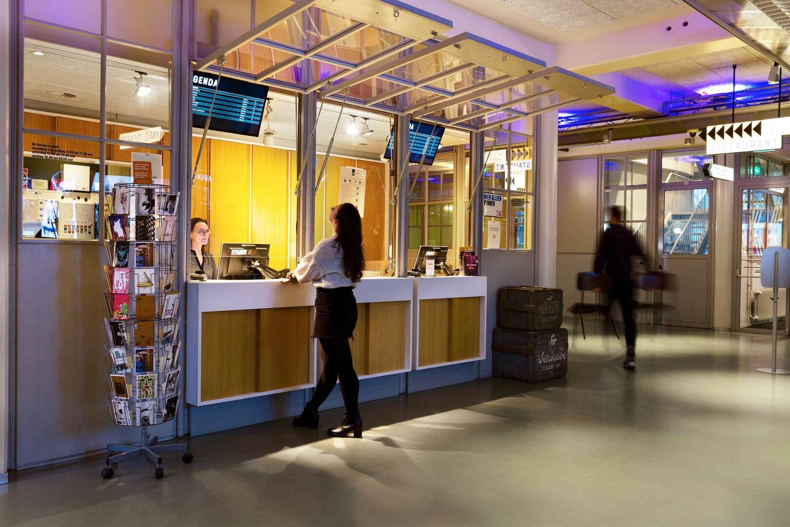 Receptie van een moderne ruimte met een vrouwelijke medewerker en een bezoeker aan de balie.