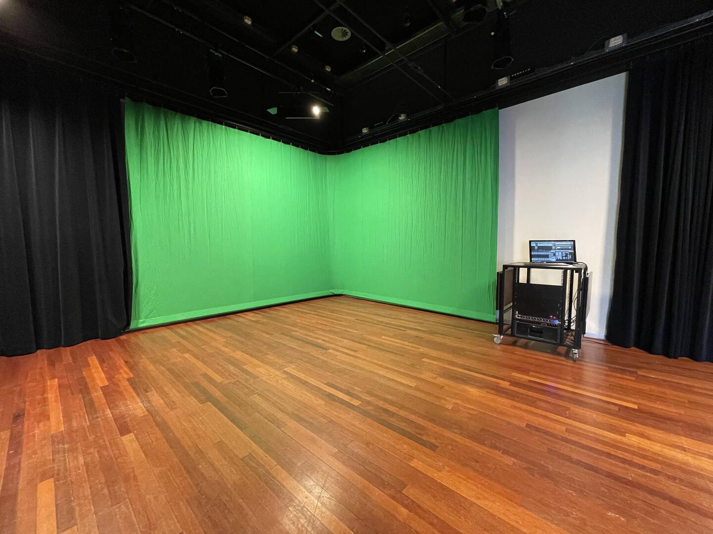 Lege studio met een groene scherm achterwand en een computer op een tafeltje, geschikt voor videoproducties.