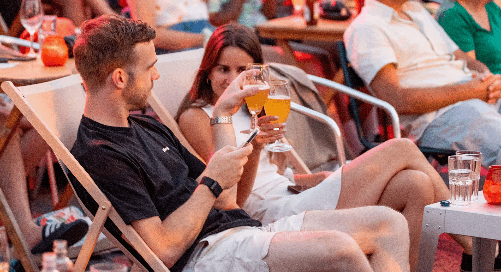 Mensen genieten van drinks op een evenement, terwijl ze ontspannen in een informele setting met stoelen en tafels.