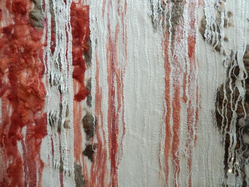 Abstracte kunstwerk met draden en texturen in tinten van rood, wit en bruin.