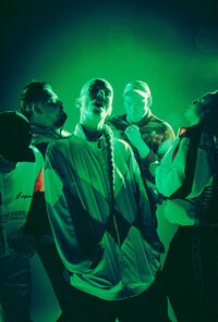 Groep mensen in sportieve kleding, met een groene lichteffect, poseren in een dynamische en expressieve manier.