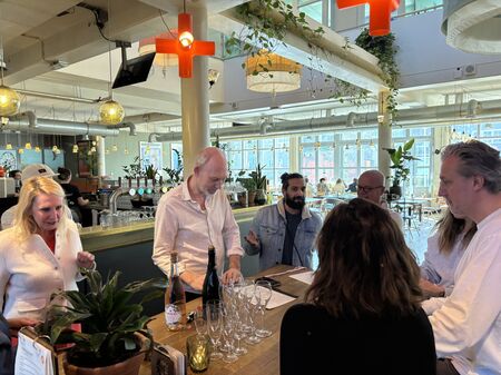 Een groep mensen in een moderne bar/lounge, genietend van een sociale bijeenkomst met champagne en planten op de tafel.