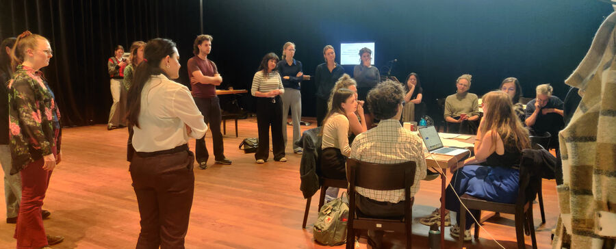 Groep mensen verzameld rond een tafel in een ruimte, betrokken in een discussie of brainstormsessie.