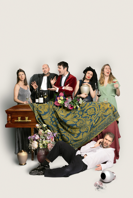 Groep mensen in verschillende kledingstijlen, met een kist, bloemen en grappige accessoires, in een theatrale opstelling.