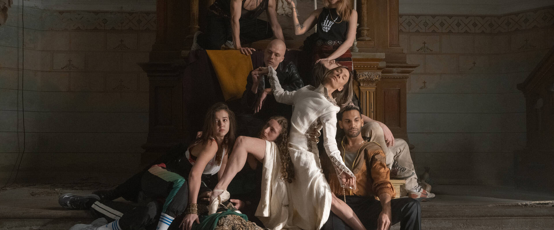 Groep vrouwen in verschillende kledingstijlen poseren creatief in een historische ruimte, met een focus op elegantie en kracht.