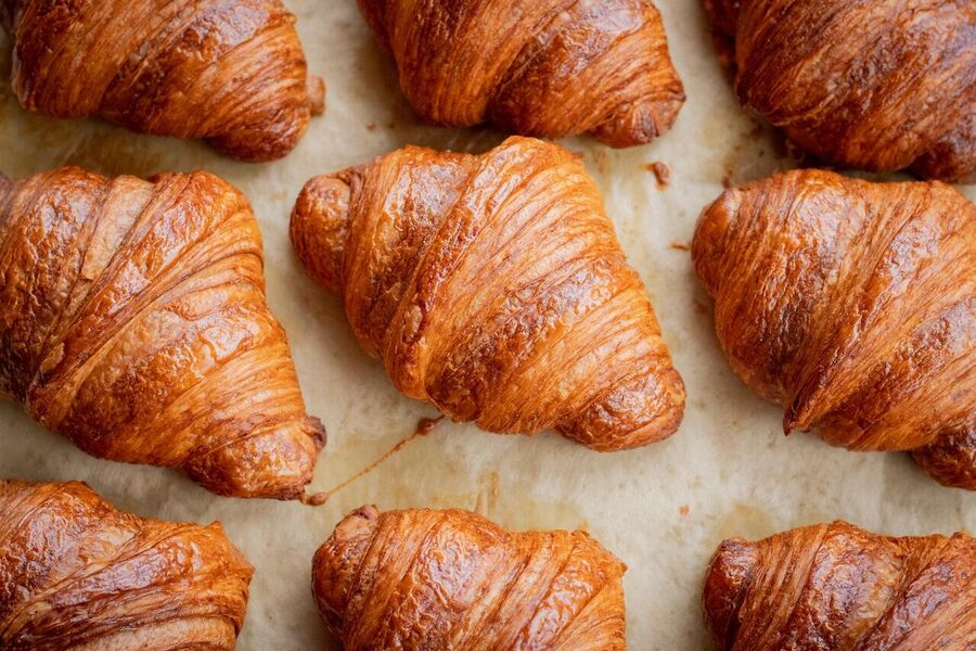Versgebakken croissants in een lichte, gouden kleur, netjes gerangschikt op bakpapier.
