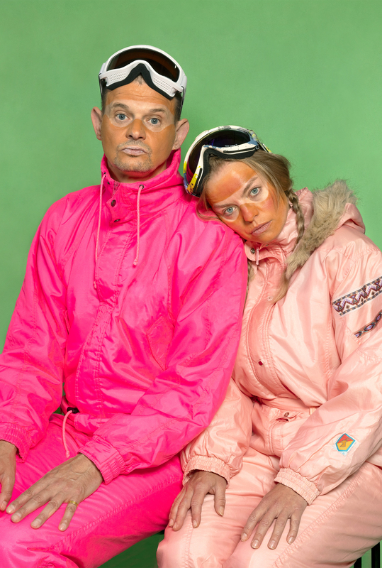 Twee mensen in felle, roze skikleding met een groene achtergrond, met een overdreven gebruinde huid.