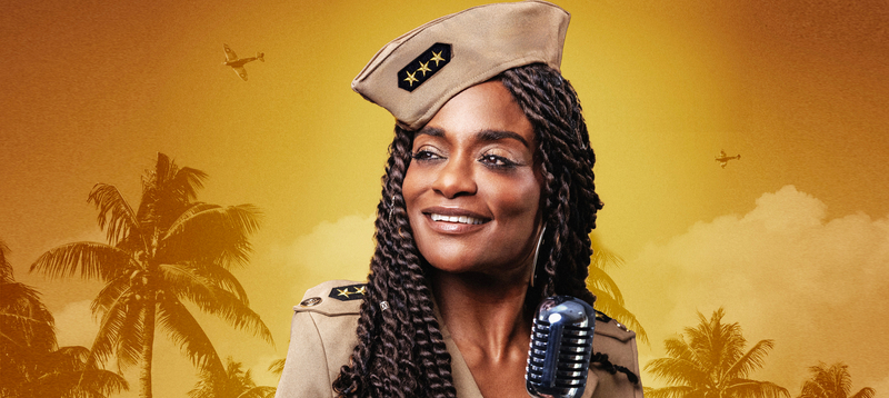 Vrouw in militaire uniform met microfoon, tegen een achtergrond van palmbomen en een oranje lucht.