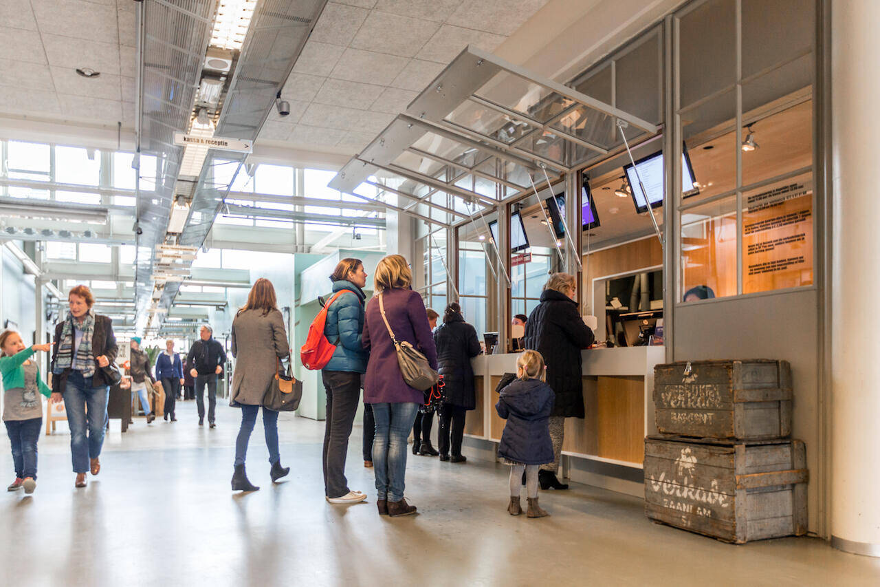 Drukke omgeving met mensen in een hal, wachtend bij de kassa van de Verkadefabriek.