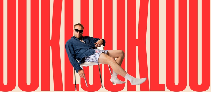 Man in een casual outfit met zonnebril, liggend op een achtergrond met herhalende tekst "JUK JUK JUK".