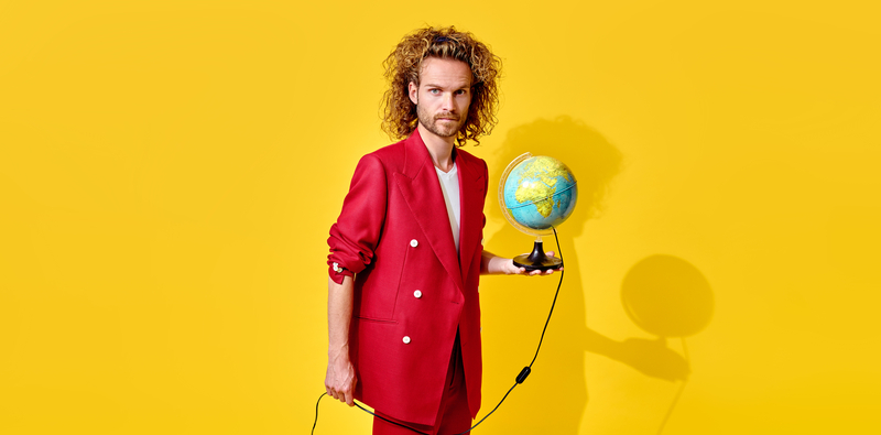 Man in een rode suit houdt een globe vast voor een heldergele achtergrond.