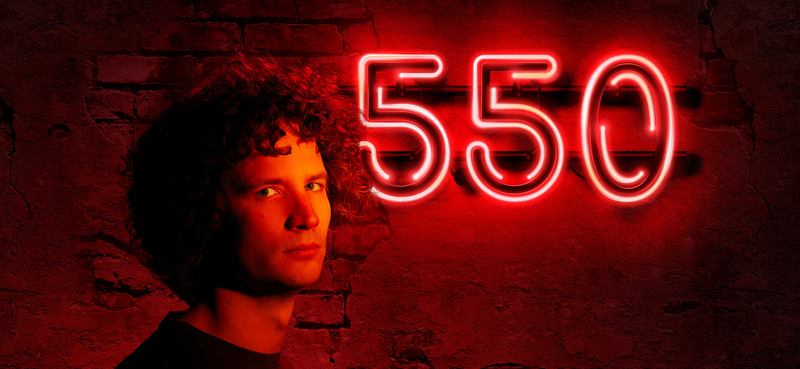 Jonge man met krullend haar staat voor een felrode achtergrond met de neontekst "550".