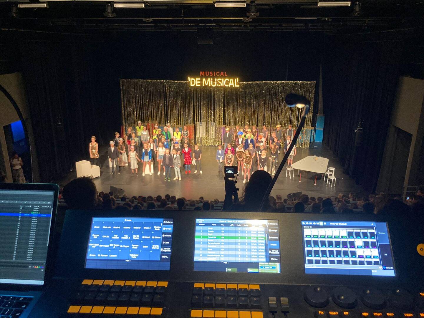 Een podium met een musicalcast, gefotografeerd vanuit de licht- en geluidsconsole.
