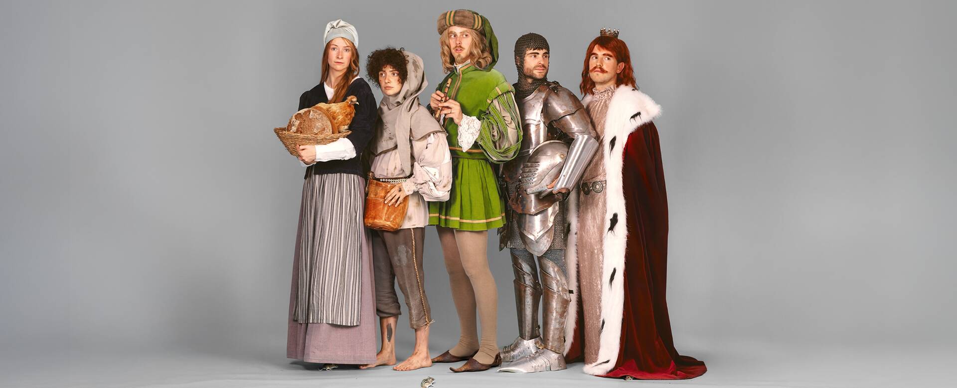 Vijf mensen in historische kostuums, variërend van een koninklijke outfit tot inwoners uit een middeleeuwse setting.